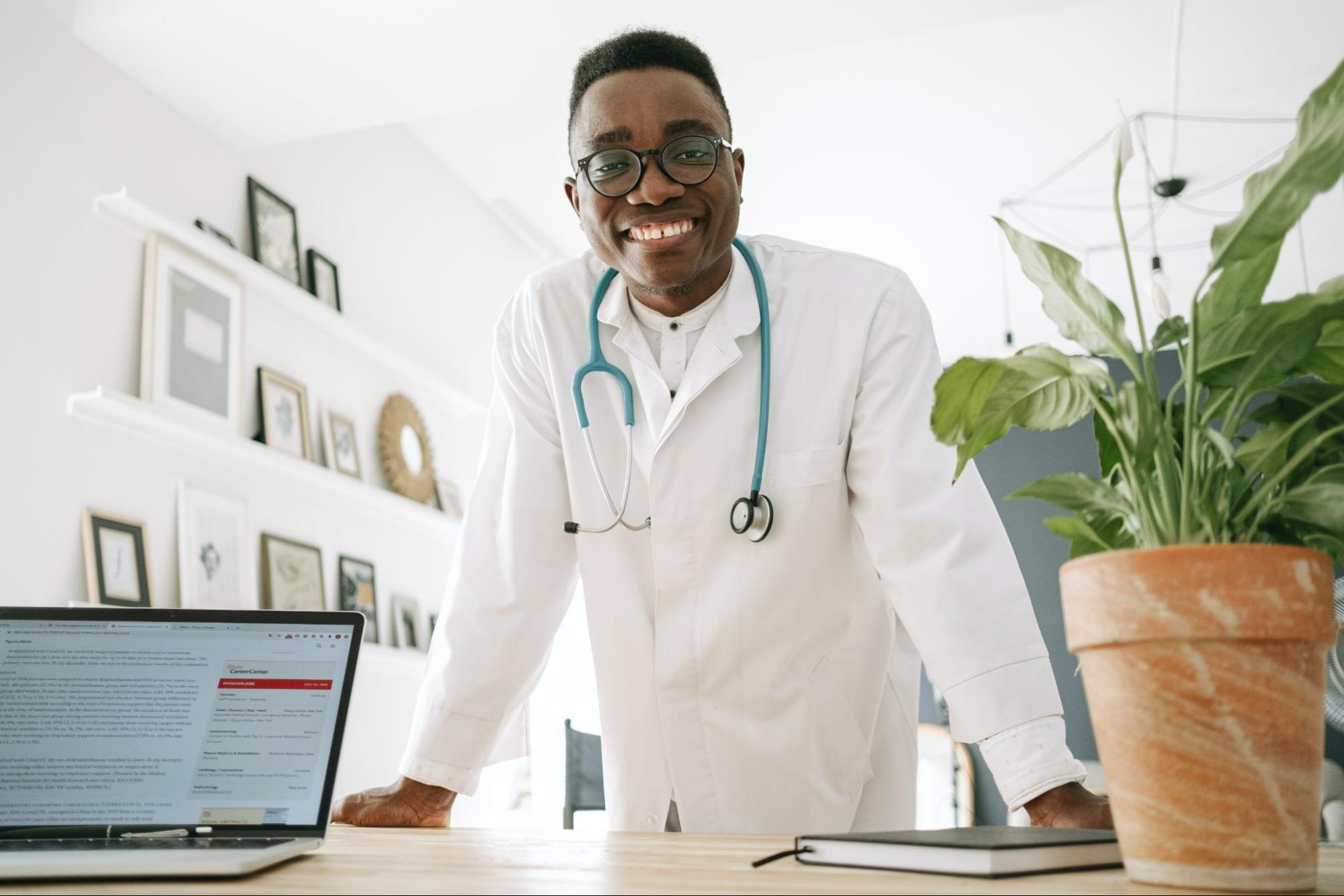 Doctor smiling with clinical pharmacist notes on laptop