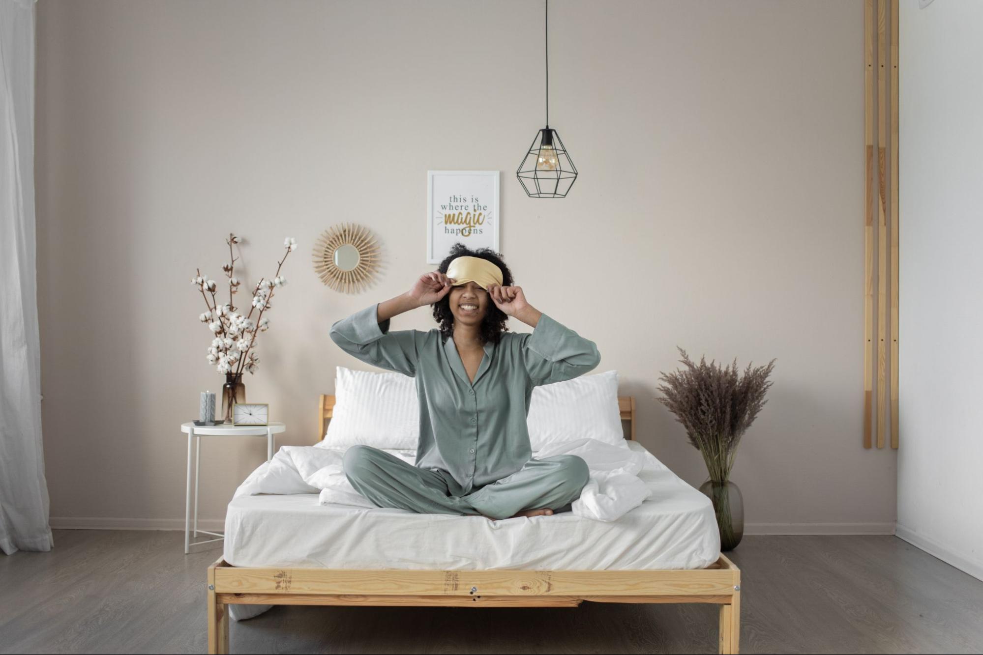 Smiling woman in bed sitting with eye cover after magnesium infusion