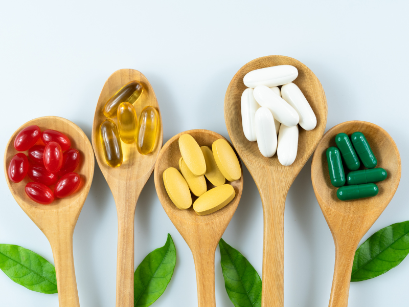 Pill and tablet skin supplements on spoons in floral arrangement