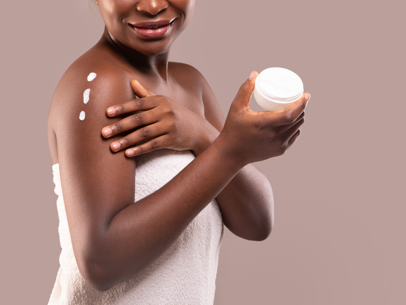 Black woman applying skin lotion to help skin barrier