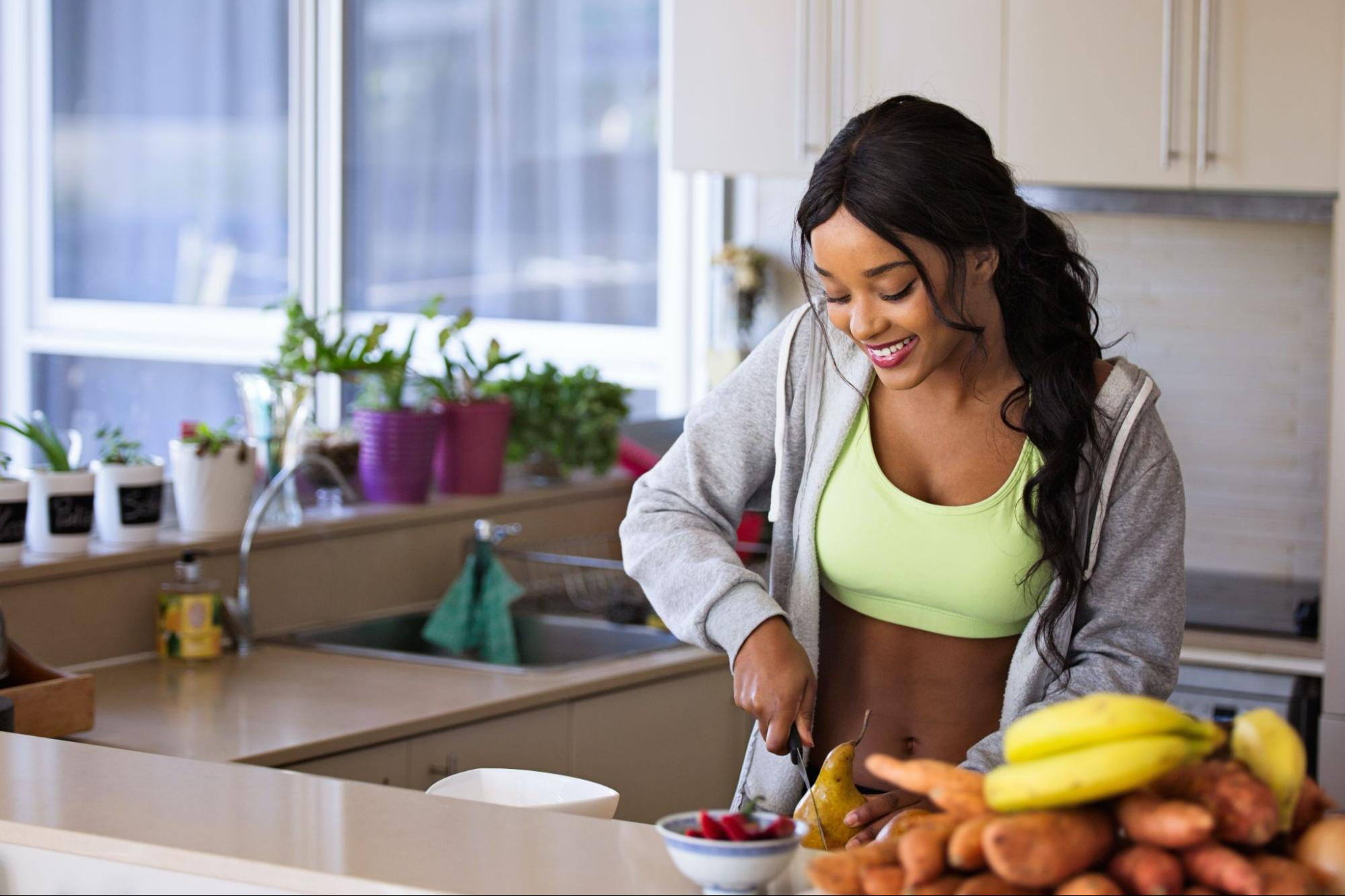 Black woman happily cutting fruit after recovering from mild depression